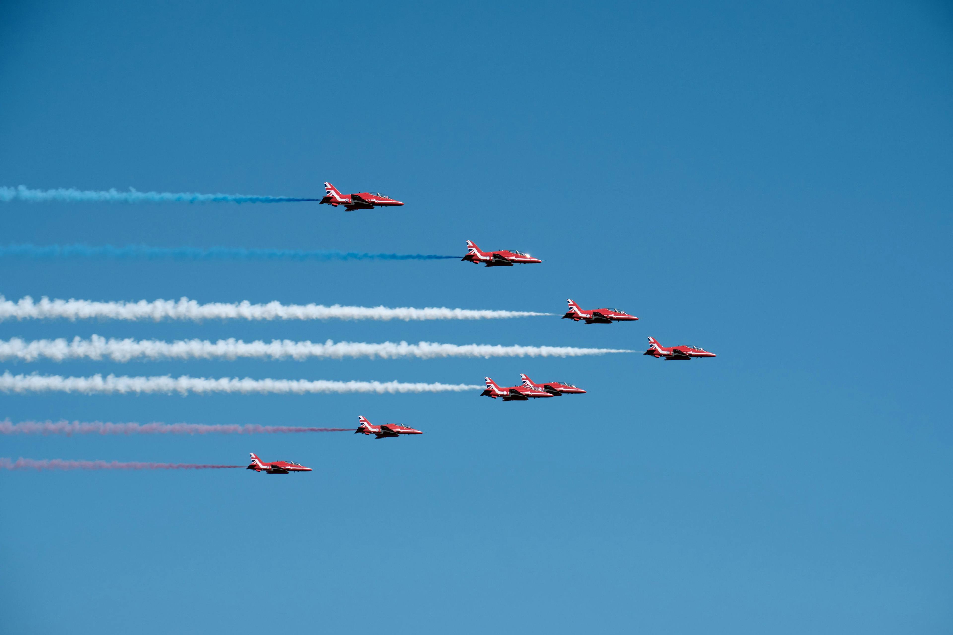 The Red Arrows fly in an arrow formation, with the blue, white and red smoke trailing
