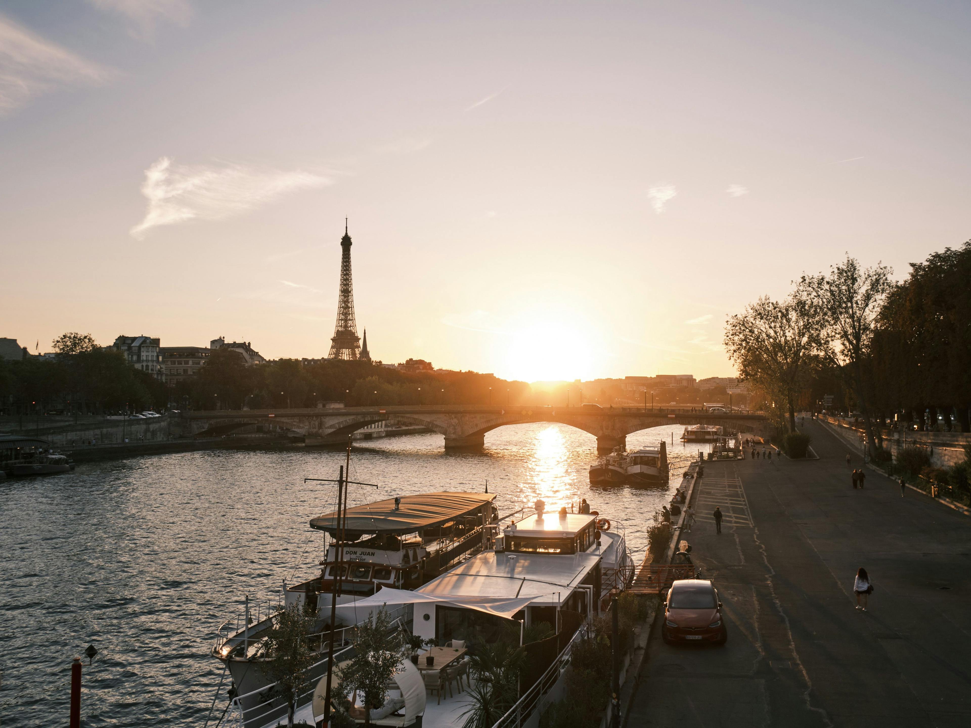 The Seine river looking towards the Eiffel Tower. The sun is setting behind the bridges creating a golden light
