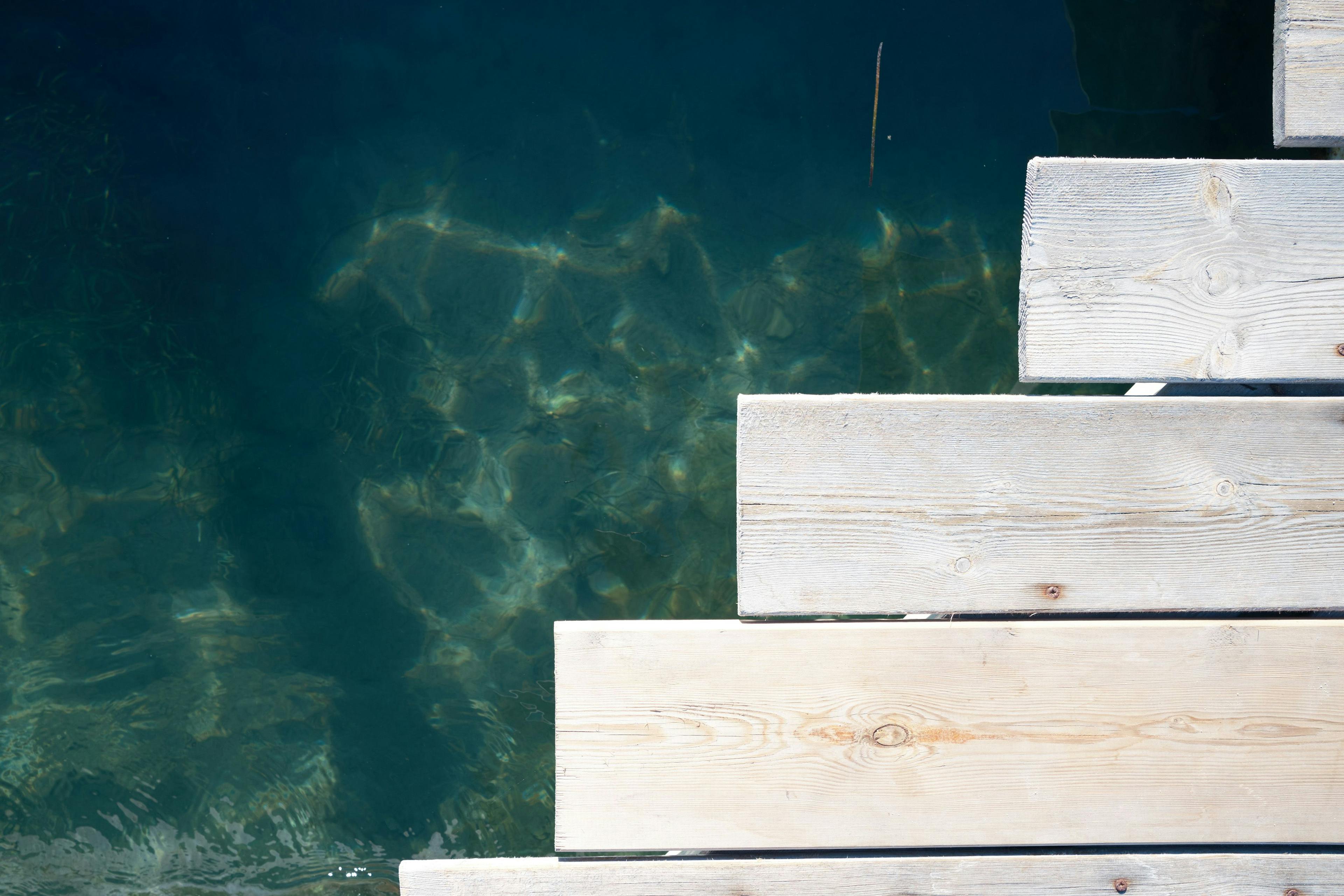 Looking down at boards of a jetty. The shape of the slats forms a step when viewed at this perspective